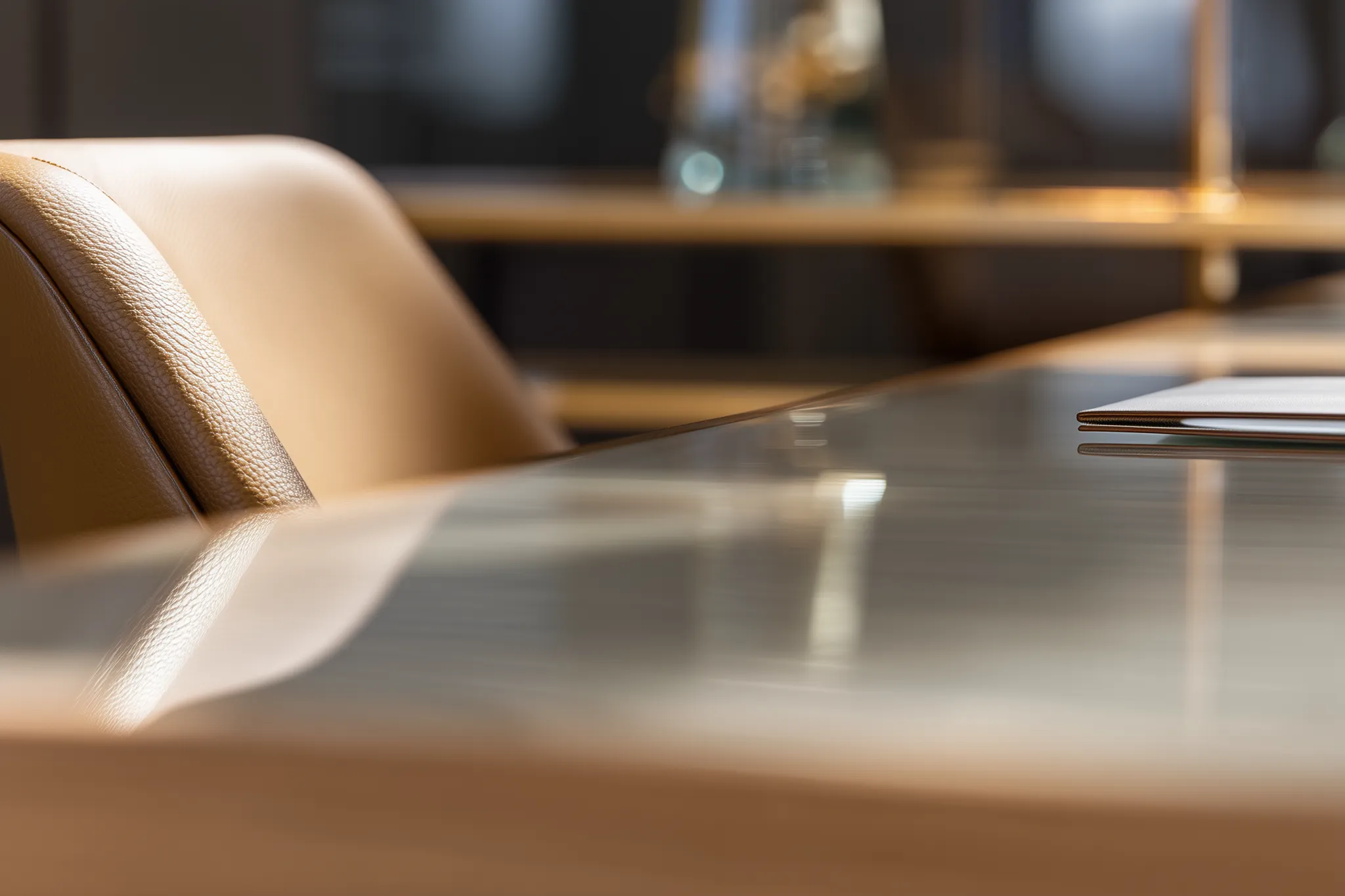 Close-up of a tan leather office chair next to a glossy conference table with a laptop on it.